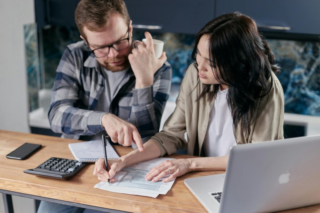 pexels-photo-6964107-6964107 A couple analyzing financial documents with calculator and laptop on a table.